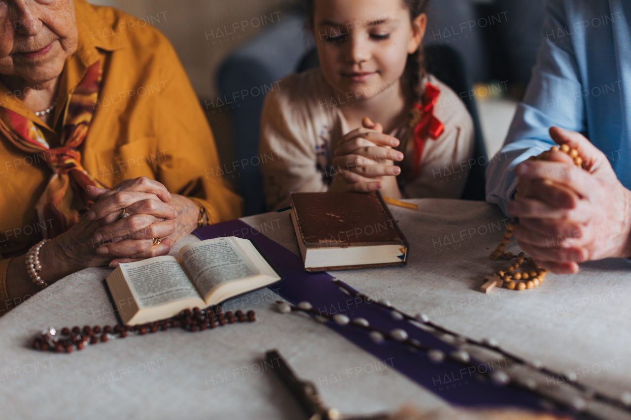 Grandparents praying during Easter with granddaughter. The Bible on table at home. Preparing for church serice. Easter as religious holiday in Christianity.