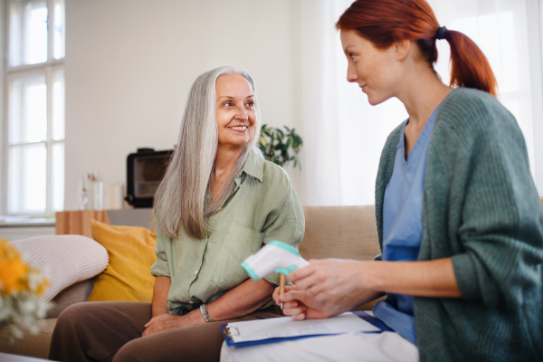 Nurse cosulting with senior woman her health condition at her home.