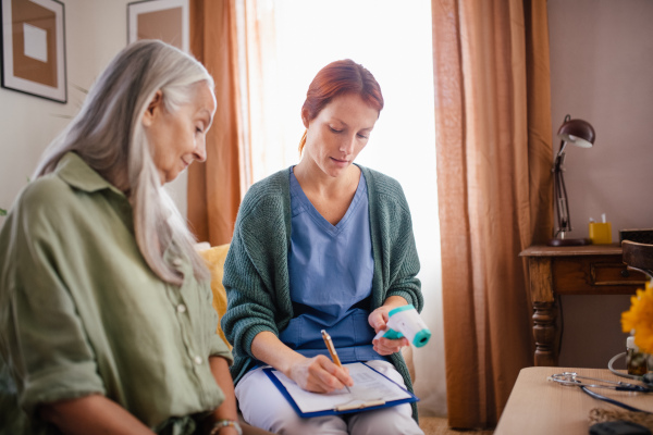 Nurse cosulting with senior woman her health condition at her home.