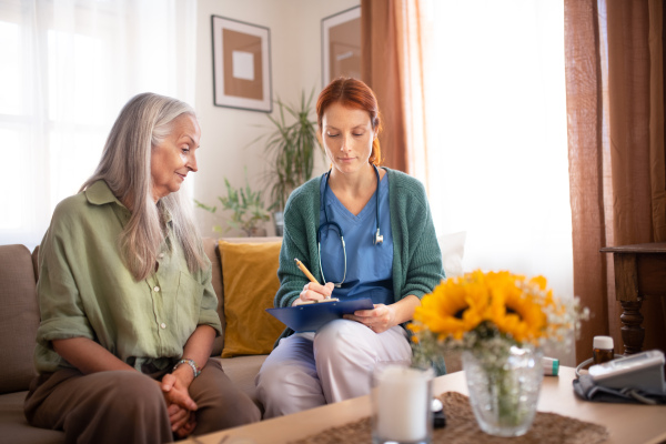 Nurse cosulting with senior woman her health condition at her home.