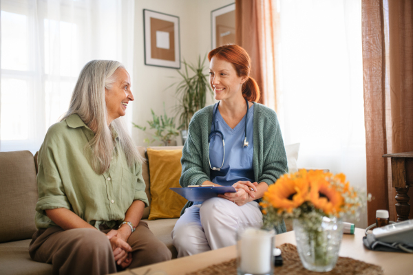 Nurse cosulting with senior woman her health condition at her home.