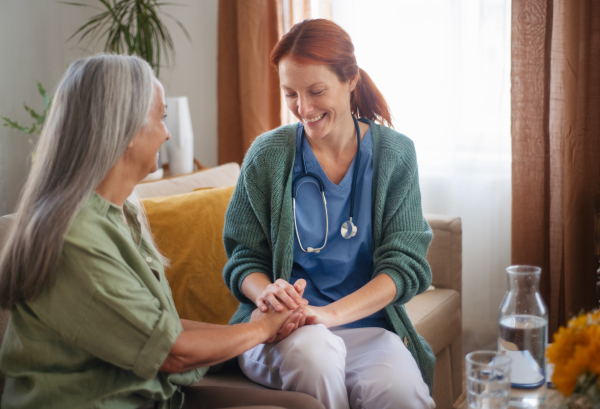 Portrait of caregiver holding hand to senior client.