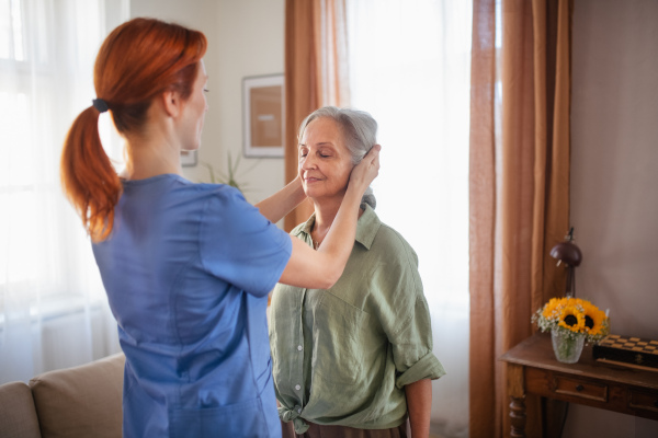 Nurse exercising with senior woman at her home, concept of a healthcare and rehabilitation.