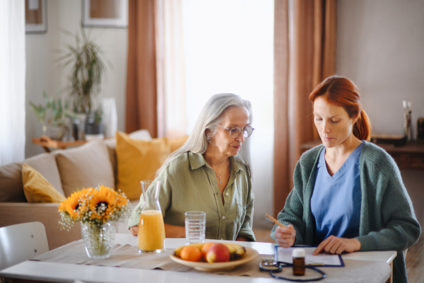 Nurse cosulting with senior woman her health condition at her home.