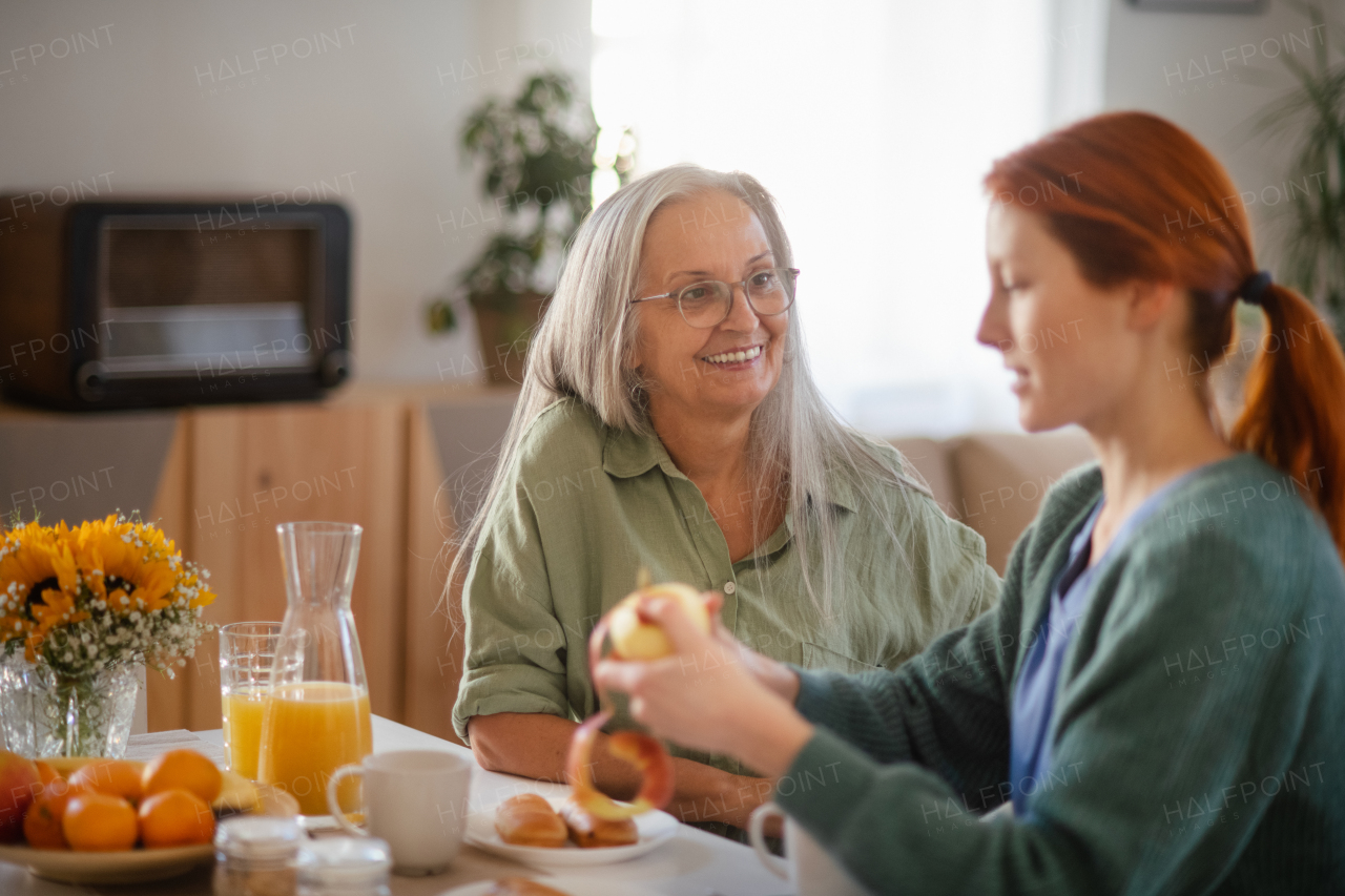 Cregiver preparing breakfast for a senior client in a bed.