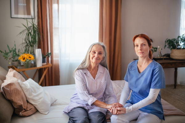 Portrait of caregiver holding hand to senior client.