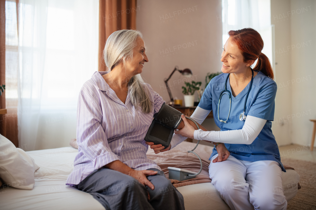 Nurse measuring blood pressuer to senior woman in her home.