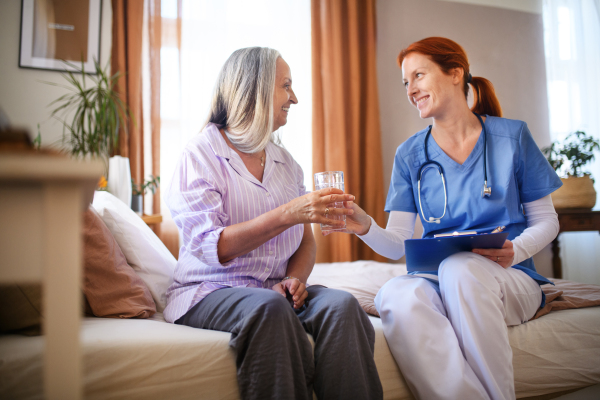 Nurse cosulting with senior woman her health condition and taking pills, at her home.