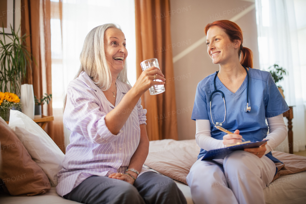 Nurse cosulting with senior woman her health condition and taking pills, at her home.