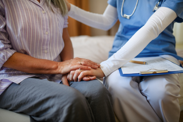 Close-up of caregiver holding hand to senior client.