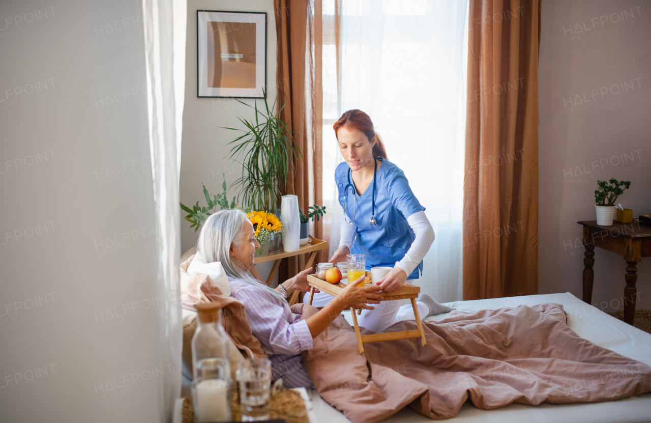 Cregiver prepared breakfast for a senior client in a bed.