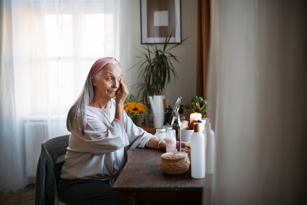 Senior woman making make up herself in home.