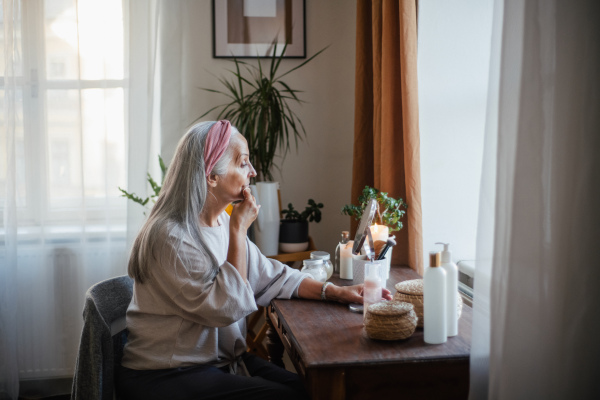 Senior woman making make up herself in home.