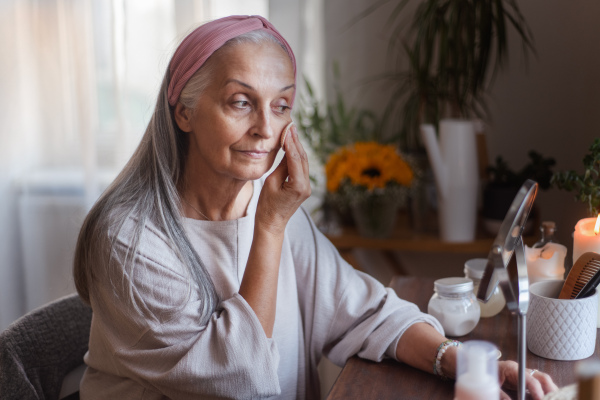 Senior woman making make up herself in home.