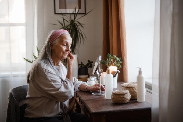 Senior woman making make up herself in home.