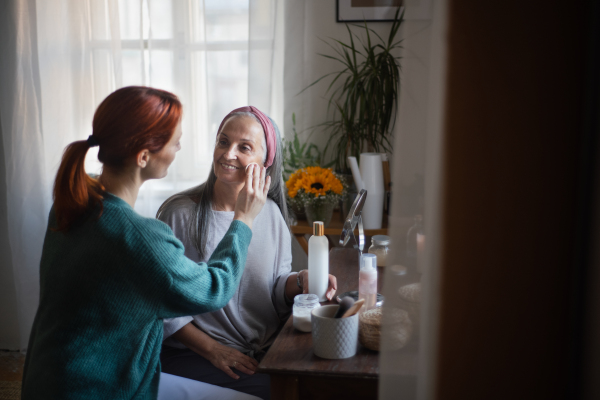 Caregiver helping her senior client with a make up.