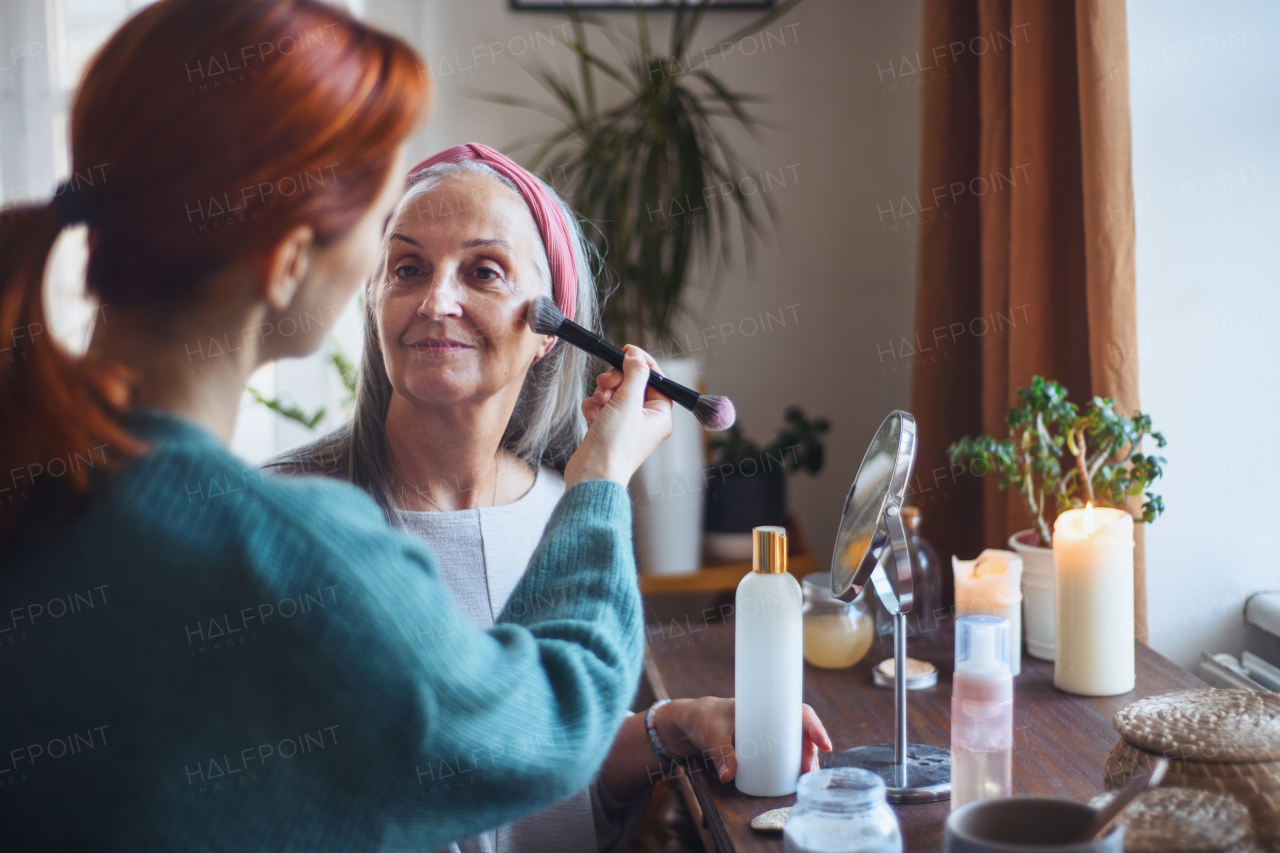 Caregiver helping her senior client with a make up.