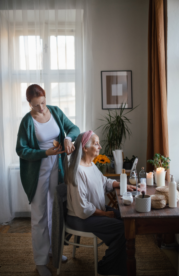 Caregiver helping her senior client with hairstyle.