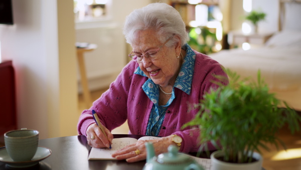 A video of elderly woman solving sudoku puzzles at home, sitting in living room. Sudoku as popular game for aging people, logical thinking, problem solving.