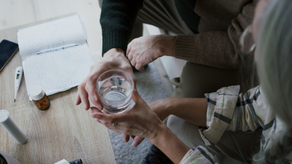 A close-up of senior man giving his wife medication at home