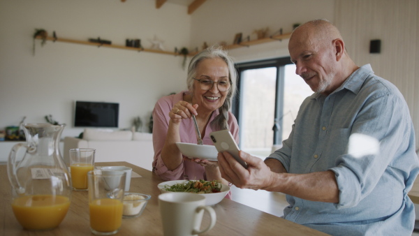 A happy senior couple eating dinner together at home.