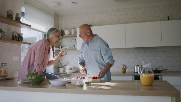 A happy senior couple cooking together at home.