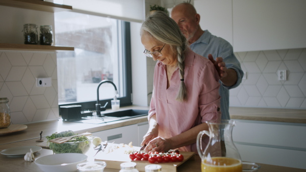 A happy senior couple cooking together at home.