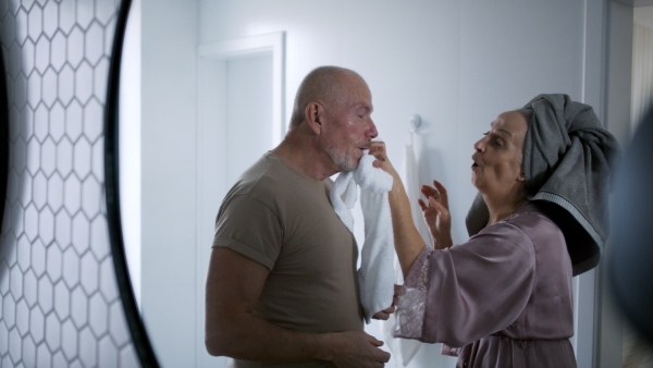 A senior couple in bathroom, washing, having fun, morning routine concept.