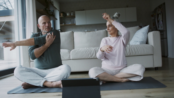 A senior couple doing relaxation exercise together at home.