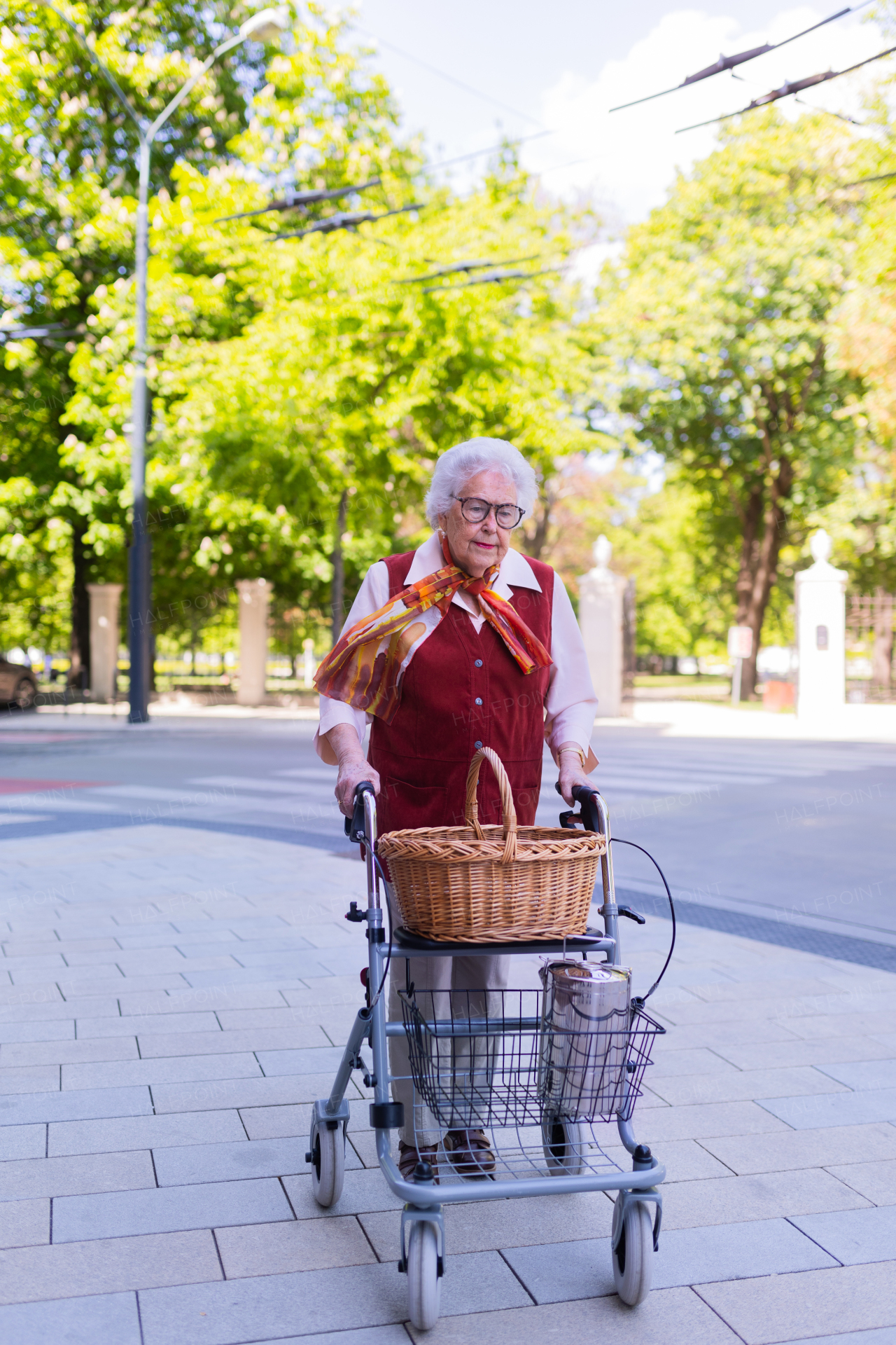 Beautiful senior woman on walk through the city, walking with the help of a rollator.