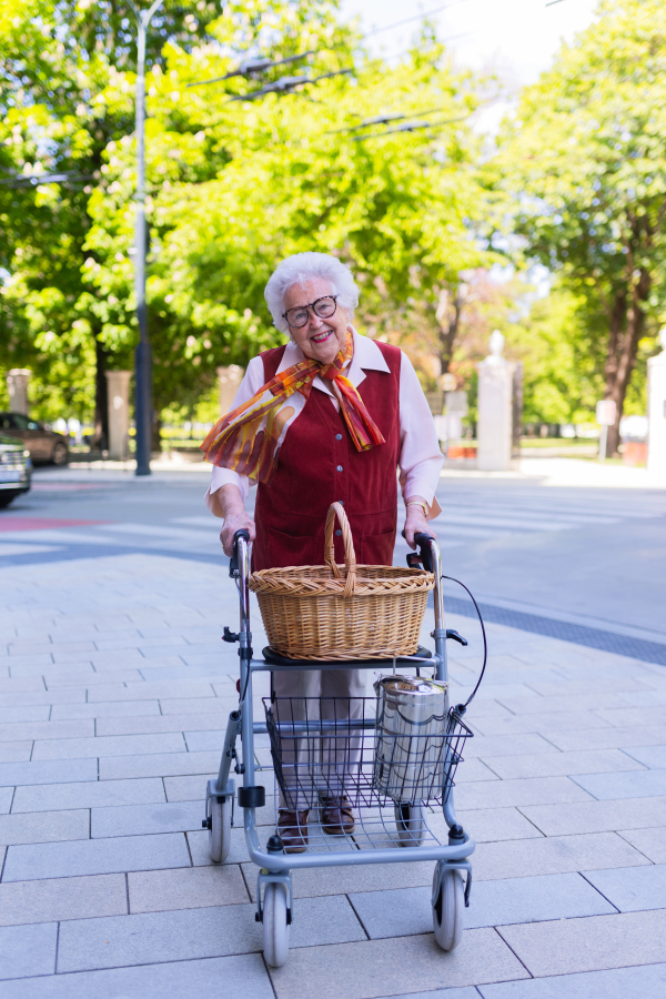 Beautiful senior woman on walk through the city, walking with the help of a rollator.