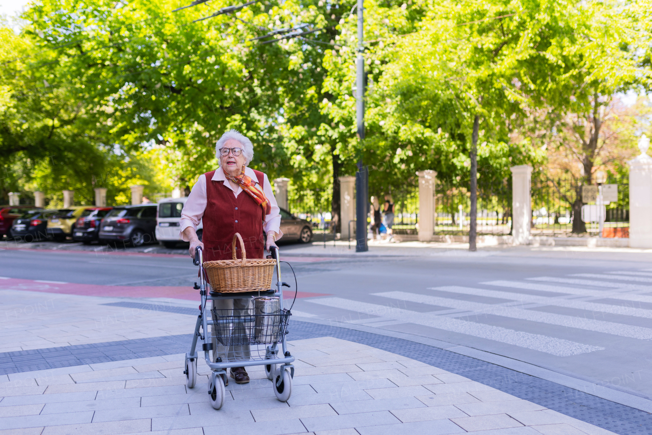 Beautiful senior woman on walk through the city, walking with the help of a rollator.