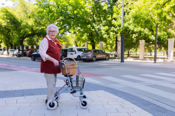 Beautiful senior woman on walk through the city, walking with the help of a rollator.