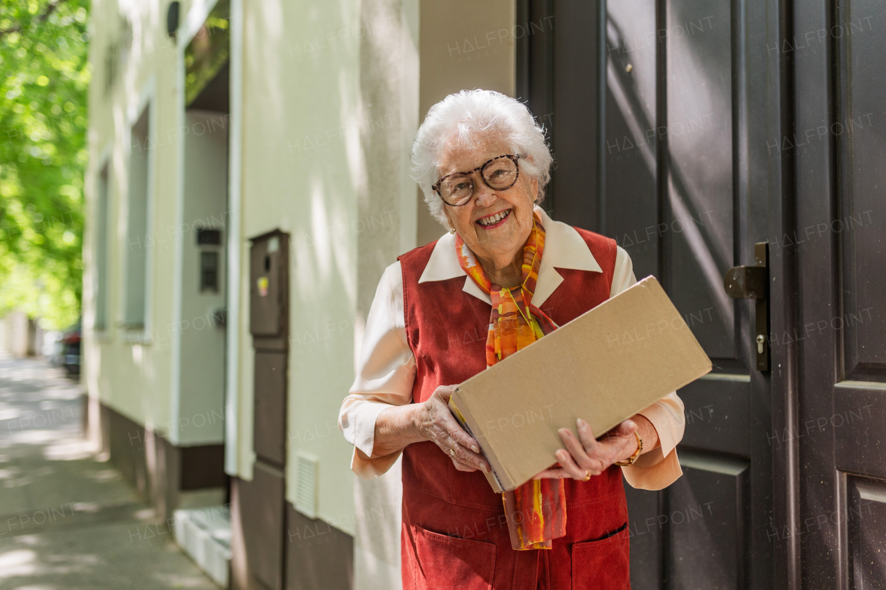 Elderly woman in front of her house, picking up package from the courier.