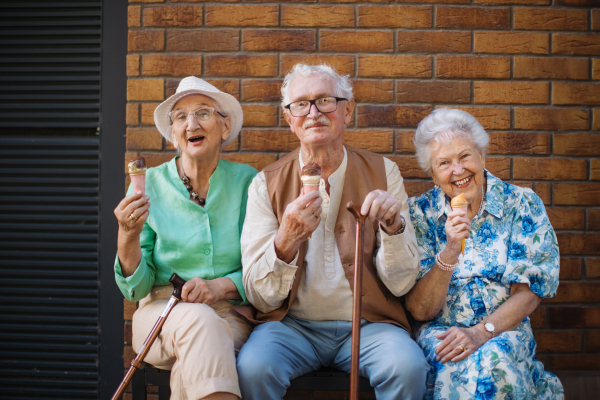 Portrait of three senior friends in the city, eating ice cream on a hot summer day. Elderly ladies on summer vacation in the city. Pensioners on group trip. Concept of senior vacation and travel groups, clubs.