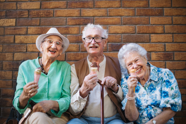 Portrait of three senior friends in the city, eating ice cream on a hot summer day. Elderly ladies on summer vacation in the city. Pensioners on group trip. Concept of senior vacation and travel groups, clubs.