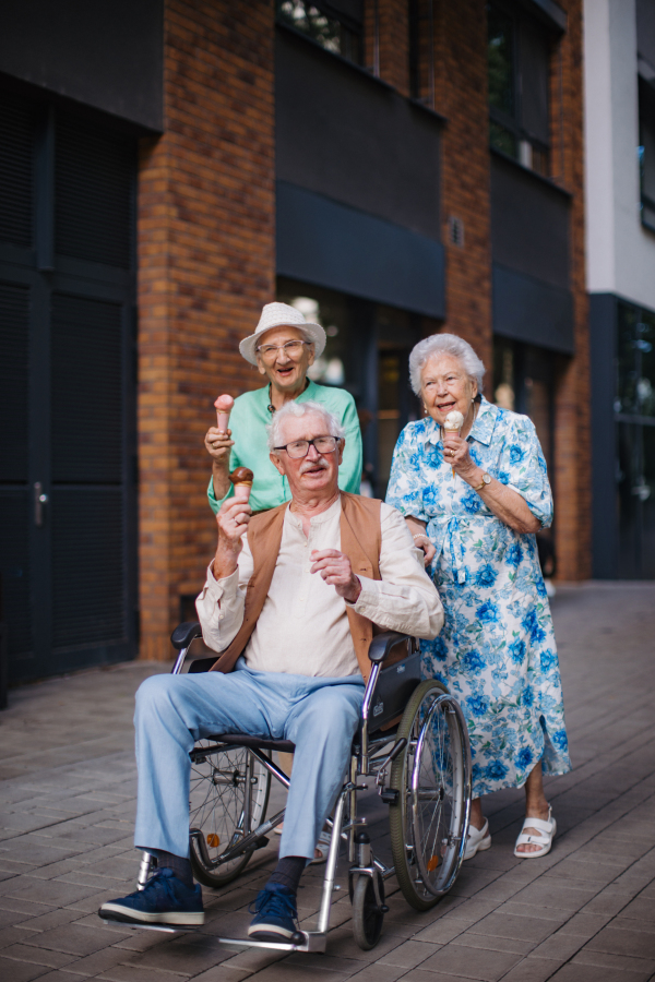 Portrait of three senior friends in the city, eating ice cream on a hot summer day. Elderly ladies on summer vacation in the city. Pensioners on group trip. Concept of senior vacation and travel groups, clubs.