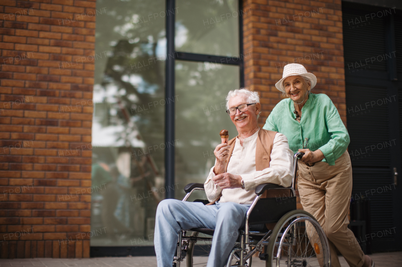 Portrait of senior couple with man in wheelchair. Elderly woman pushing her delightful husband in wheelchair. Concept of chronic illness in elderly couple. Portrait with copy space on black background. Senior siblings spending quality time together.