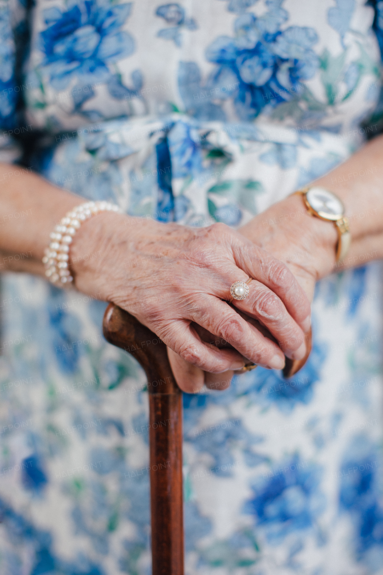 Close-up of a senior woman's hands holding a walking cane. Old lady with wrinkled skin on arms and vintage jewelry.