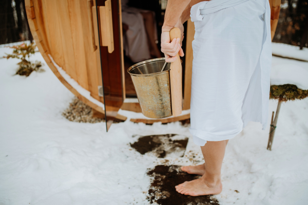 Low angle view of seniors entering in to outdoor hot tub with a pail.