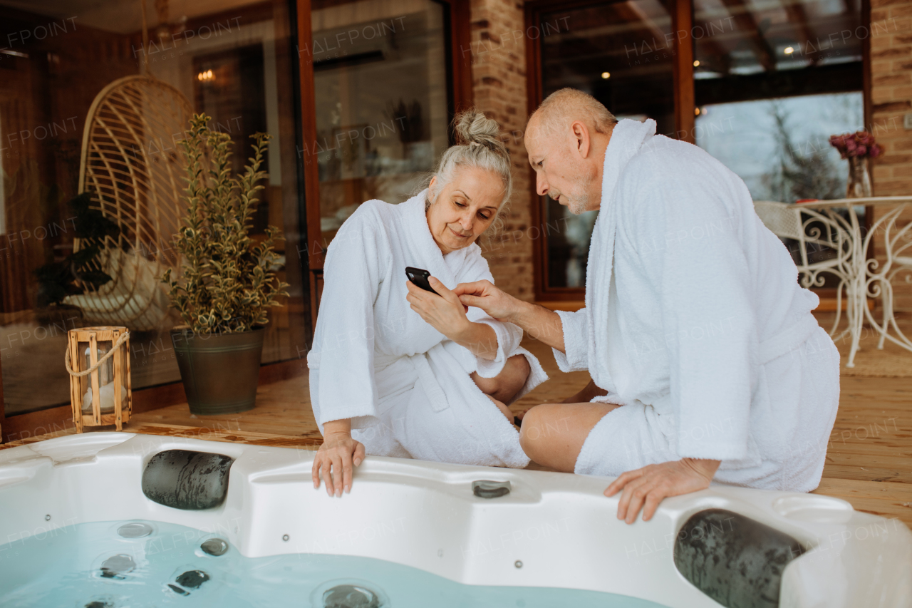 Senior couple prepare outdoor bath tub and chcecking a smartphone.