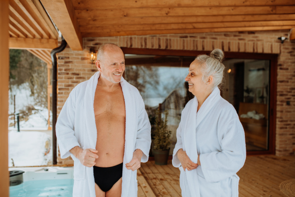 Senior couple standing in terrace and preparing for outdoor bathing during a cold winter day.