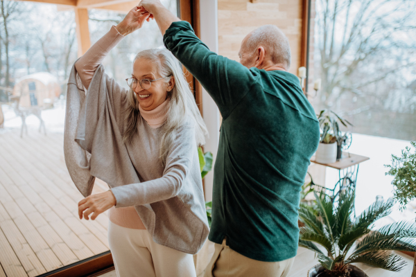 Senior couple in love dancing together in their nice modern living room.