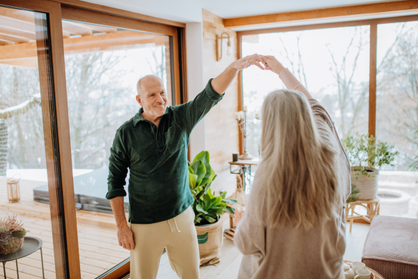 Senior couple in love dancing together in their nice modern living room.