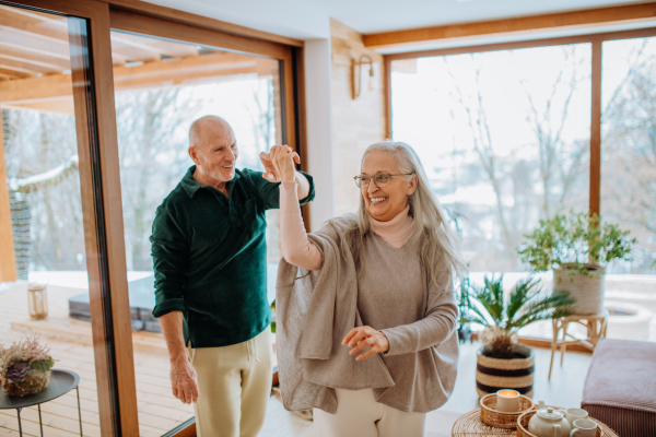 Senior couple in love dancing together in their nice modern living room.