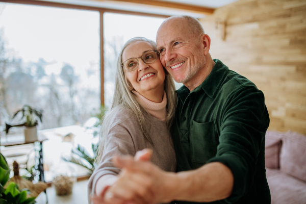 Senior couple in love dancing together in their nice modern living room.