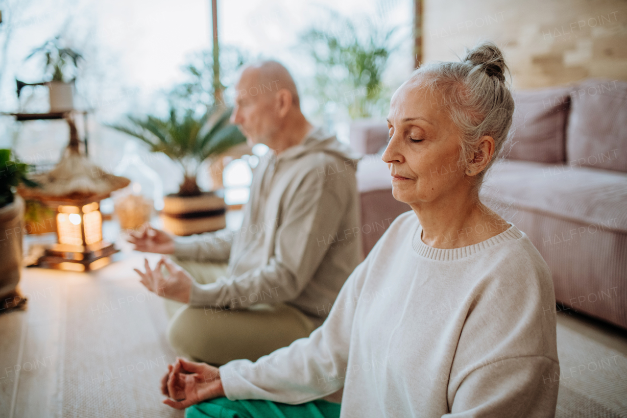 Senior couple meditating together in their living room during a cold autumn day.