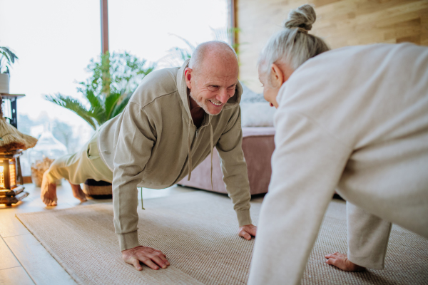 Senior couple exercising together in their living room during a cold autumn day.