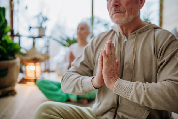 Senior couple meditating together in their living room during a cold autumn day.