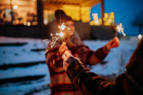 Happy senior couple celebrating new year with the sparklers, enjoying winter evening.